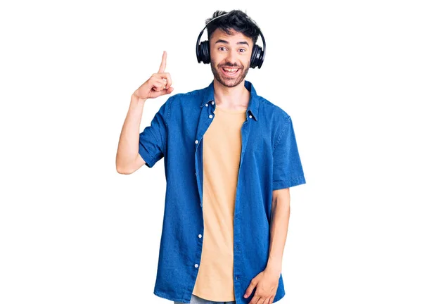 Jovem Hispânico Ouvindo Música Usando Fones Ouvido Apontando Dedo Para — Fotografia de Stock