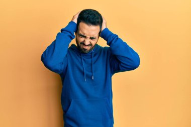 İspanyol asıllı genç adam gündelik giysiler giyiyor. Baş ağrısı çekiyor. Acı ve migren yüzünden çaresiz ve stresli. Eller başının üstünde.. 