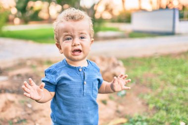 Güneşli bir günde parkta öfke nöbeti geçirirken ağlayan tatlı ve üzgün bir çocuk. Güzel sarı saçlı erkek çocuk dışarıda gözyaşları içinde hayal kırıklığına uğradı.