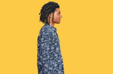 80 'lerden kalma tişört giyen Afro-Amerikan genç adam, rahat bir görünüm takınıyor, doğal bir yüz ifadesi ve kendine güvenen bir gülümsemeyle.. 