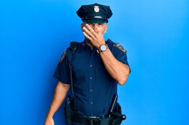 Orta yaşlı, polis üniforması giyen yakışıklı bir adam pis ve iğrenç bir koku alıyor. Nefesini burnunda tutuyor. Kötü kokuyor. 