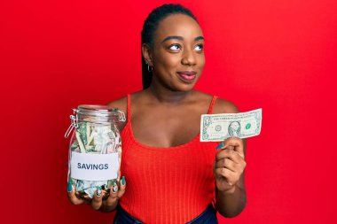 Genç Afro-Amerikalı kadın elinde kavanozla elinde 1 dolarlık banknot, gülümsüyor ve şöyle düşünüyor:. 