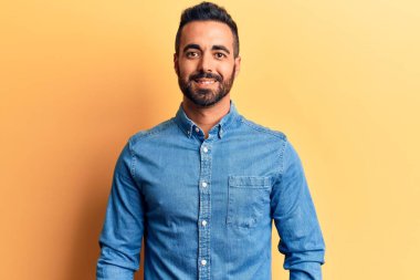 Yüzünde mutlu ve havalı bir gülümseme olan sıradan kıyafetler giyen genç İspanyol bir adam. şanslı kişi. 