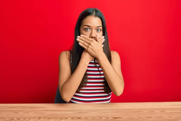 Schöne Hispanische Frau Lässiger Kleidung Auf Dem Tisch Sitzend Schockiert — Stockfoto