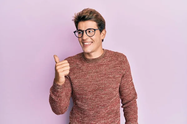 일상적 스웨터를 안경을 얼굴로 웃으면서 엄지로 옆쪽을 가리키는 잘생긴 코카서스 — 스톡 사진