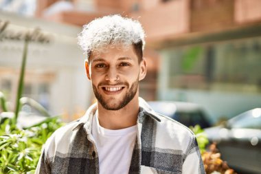 Genç İspanyol adam gülümseyerek şehirde mutlu mesut dikiliyor..