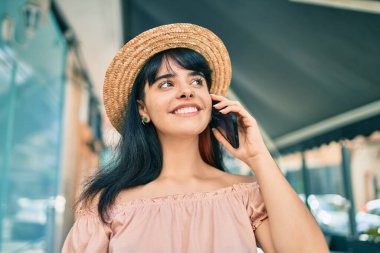 Yaz stili giyinmiş genç İspanyol turist kız şehirde akıllı telefondan konuşuyor..