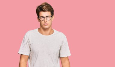 Yakışıklı beyaz bir adam günlük kıyafetler ve gözlük takıyor. Uykulu ve yorgun görünüyor. Yorgunluktan ve akşamdan kalmalıktan yorgun.. 