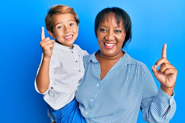 母と息子のヒスパニック系の家族一緒に抱きしめる愛と一緒に笑顔でアイデアや質問を指差す指で幸せな顔 ナンバーワン — ストック写真