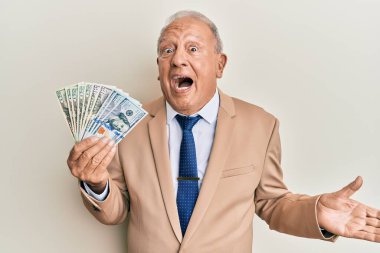 Kıdemli beyaz adam elinde dolarlarla başarıyı mutlu bir gülümsemeyle kutluyor ve kazanan el kaldırarak ifade ediyor. 