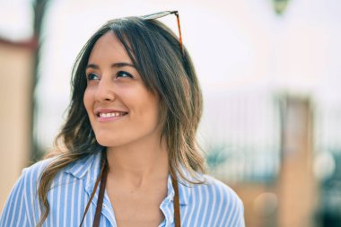 Genç İspanyol kadın gülümseyerek şehirde mutlu mesut dikiliyor..