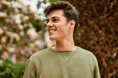 Genç İspanyol adam gülümseyerek şehirde mutlu mesut dikiliyor..