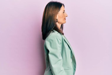 Orta yaşlı esmer kadın, sıradan kıyafetler giyiyor, rahat bir görünüm takınıyor, doğal bir yüz ve kendine güvenen bir gülümsemeyle poz veriyor.. 