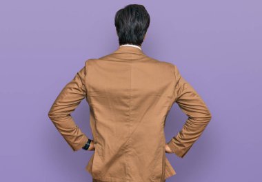 İş kıyafetleri giymiş genç İspanyol adam kolları vücudunda geriye doğru bakıyor. 