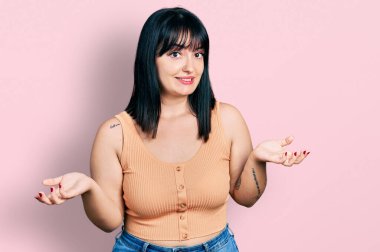 Young hispanic plus size woman wearing casual clothes clueless and confused expression with arms and hands raised. doubt concept. 