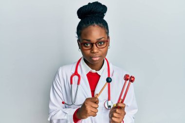 Doktor üniforması giyen genç Afro-Amerikan kadın elinde çatal tutarken yüzünde ciddi bir ifade vardı. Basit ve doğal bir şekilde kameraya bakıyorsun.. 