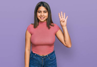 Gündelik tişört giyen genç İspanyol kız gülümseyerek kendinden emin ve mutlu bir şekilde dört numarayı gösteriyor ve işaret ediyor.. 