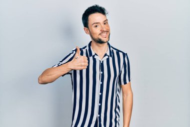 Gündelik kıyafetler giyen genç İspanyol adam elleriyle mutlu bir jest yapıyor. Kameraya bakıp başarıyı gösteren ifade. 