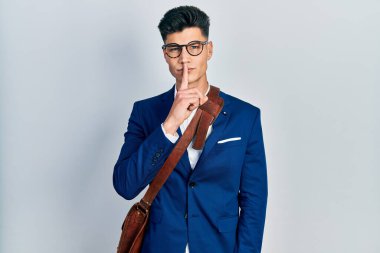 İş kıyafetleri giymiş genç İspanyol adam parmakları dudaklarında sessiz olmak istiyor. sessizlik ve gizli konsept. 