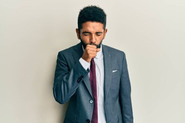 Sakallı, takım elbiseli ve kravatlı yakışıklı İspanyol bir adam kendini iyi hissetmiyor ve soğuk algınlığı veya bronşitin belirtisi olarak öksürüyor. sağlık hizmeti kavramı. 