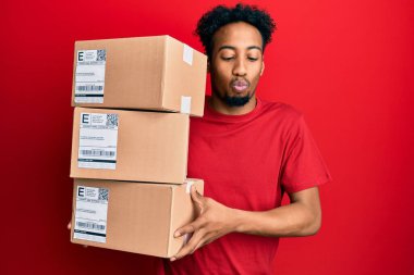 Sakallı, teslimat paketleri taşıyan, ağzı balık suratlı ve şaşı gözlü, çılgın ve komik bakışlı genç Afro-Amerikalı bir adam.. 