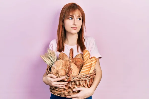 Rödhårig Ung Kvinna Håller Korg Med Bröd Leende Tittar Sidan — Stockfoto