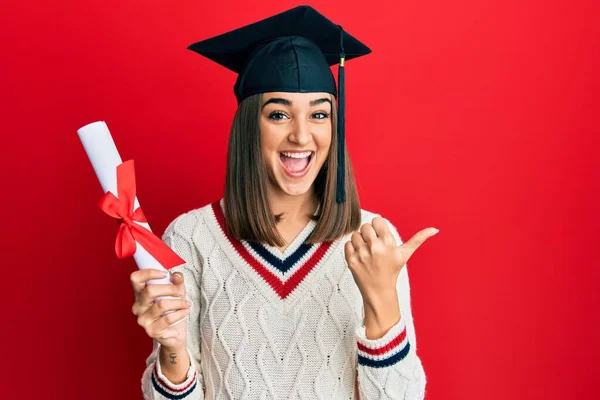 Joven Morena Sosteniendo Diploma Posgrado Apuntando Pulgar Hacia Lado Sonriendo —  Fotos de Stock