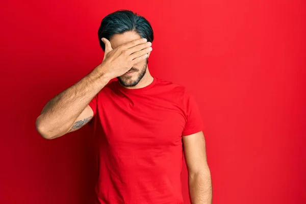 Young Hispanic Man Wearing Casual Red Shirt Covering Eyes Hand — Stockfoto