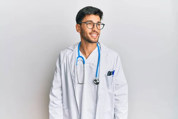 Młody Przystojny Mężczyzna Mundurze Lekarza Stetoskopie Patrzący Bok Uśmiechem Twarzy — Zdjęcie stockowe