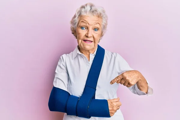 Senior Grey Haired Woman Wearing Arm Sling Smiling Happy Pointing — ストック写真