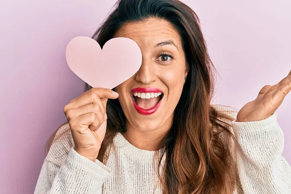 Mulher Hispânica Bonita Segurando Papel Forma Coração Cobrindo Olho Celebrando — Fotografia de Stock