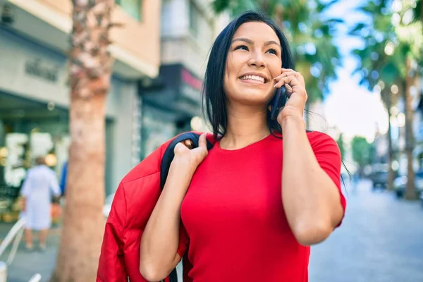 若いラテン語の女性の笑顔幸せな話上のスマートフォンで街 — ストック写真