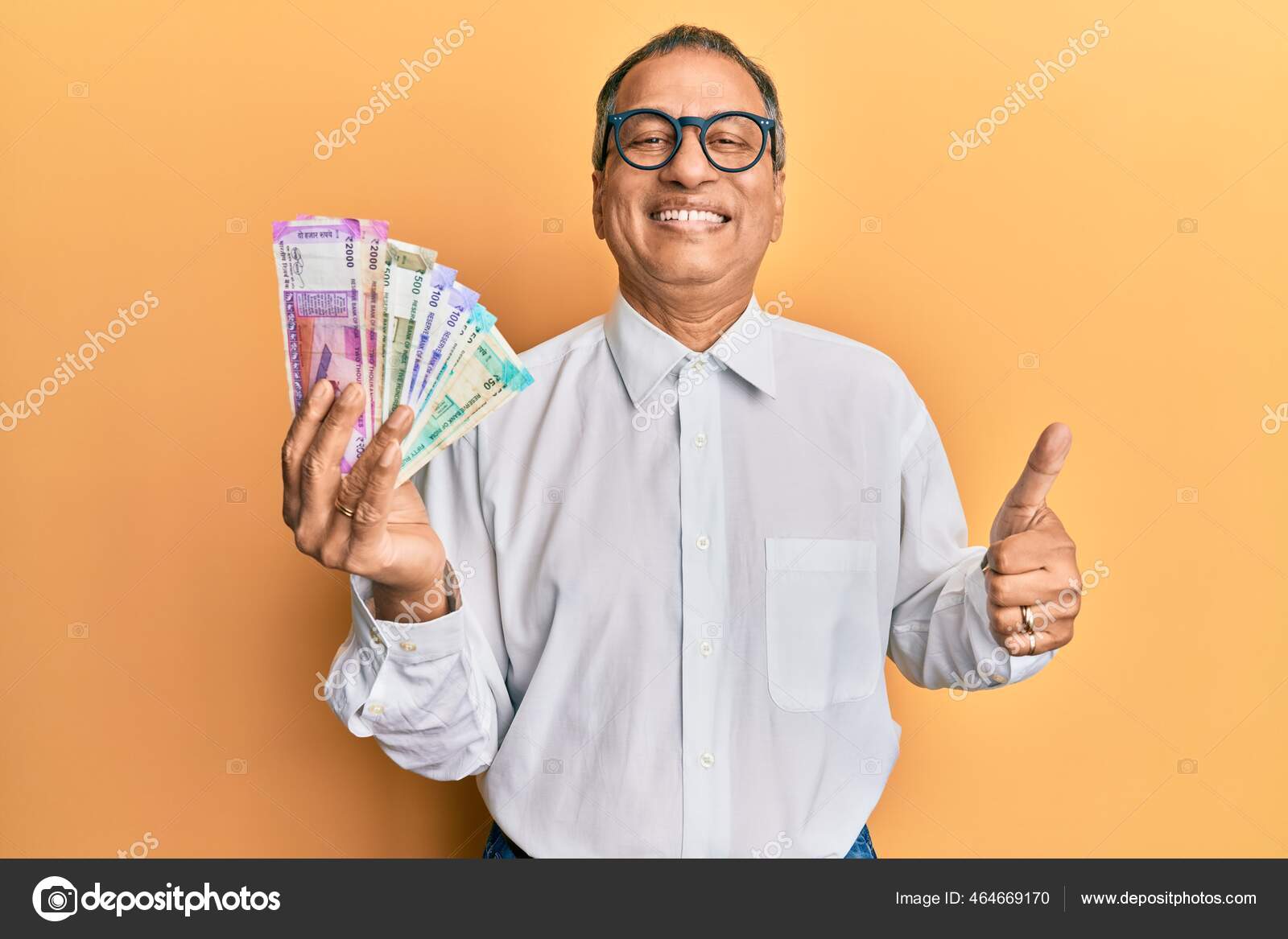 印度中年男子手里拿着印度卢比钞票面带微笑面带微笑大手笔做得出色签了字——图库图片© Krakenimages.com #464669170