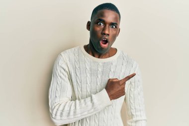 Gündelik giysiler giyen Afro-Amerikan genç adam parmaklarını yana çevirerek şaşırdı, ağzı açık hayret içinde kaldı.. 