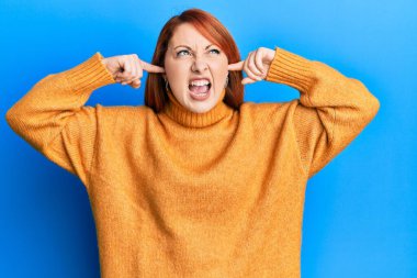 Güzel kızıl saçlı kadın parmaklarını kulaklarına koyuyor gürültüyü görmezden geliyor kızgın ve öfkeli çığlıklar atıyor, öfkeyle bağırıyor. öfke ve agresif konsept. 