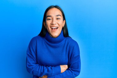 Genç Asyalı kadın, sıradan bir kazak giyiyor, gülümsüyor ve kahkahalarla gülüyor.. 