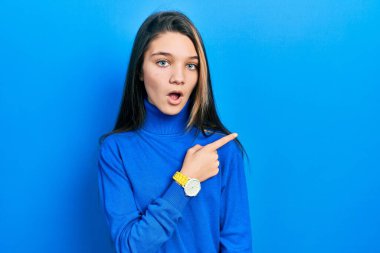 Balıkçı yaka kazak giyen genç esmer kız parmağıyla yan tarafı göstererek şaşırdı, ağzı açık hayret içinde kaldı.. 