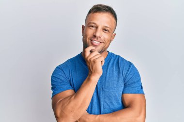 Yakışıklı, sıradan kıyafetler giyen, kameraya gülümseyen kolları çapraz ve çenesi açık bakan kaslı adam. Olumlu düşünmek. 