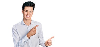 Genç İspanyol iş adamı iş kıyafetleri içinde gülümseyen ve kameraya iki eliyle ve parmaklarıyla işaret eden.. 