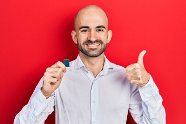 Elinde SDxc kartı tutan genç, mutlu ve pozitif gülümseyen, başparmağıyla mükemmel ve onay işareti yapan bir adam. 