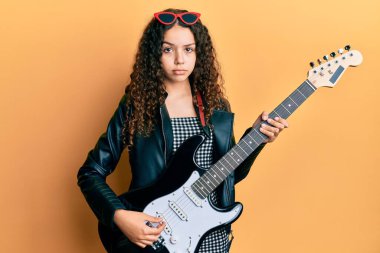 Genç İspanyol kız elektro gitarda şüpheci ve gergin oynuyor, sorun yüzünden surat asıyor. negatif kişi. 