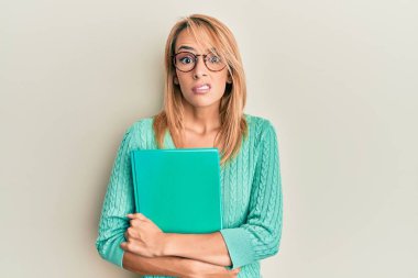 Güzel sarışın kadın elinde kitap tutuyor. Gözlüklü, budala ve kafası karışık bir ifade takınıyor. şüphe kavramı. 