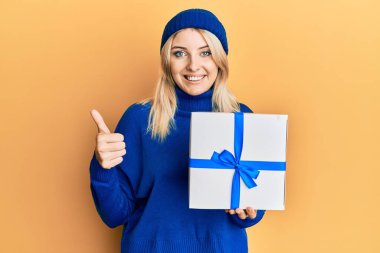 Genç beyaz kadın elinde mutlu ve pozitif bir şekilde gülümseyen, başparmağını kaldırarak mükemmel ve onaylı bir işaret veriyor. 