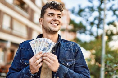 Genç İspanyol gülümseyen adam, şehirde Peru sol banknotlarını tutarken mutlu.