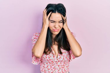 Genç esmer kadın yaz elbisesi giyiyor. Baş ağrısı çekiyor. Acı ve migren yüzünden çaresiz ve stresli. Eller başının üstünde.. 