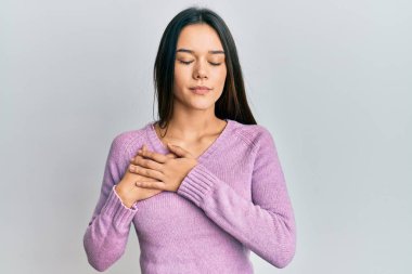 Elleri göğsünde gülümseyen, yüzünde minnet dolu bir jestle gülümseyen Latin asıllı genç bir kız. sağlık kavramı. 