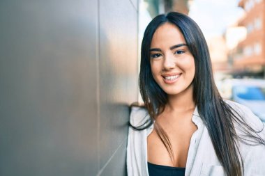 Genç İspanyol kız gülümsüyor. Mutlu bir şekilde şehrin duvarına yaslanıyor..