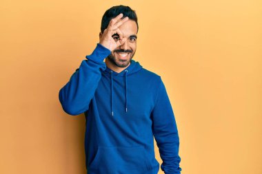 Gündelik kıyafetler giyen genç İspanyol adam el hareketleriyle gülümsüyor ve mutlu yüzüyle parmaklarından bakıyor.. 