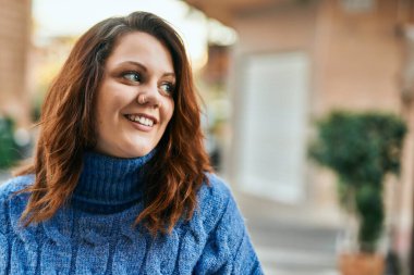 Genç İrlandalı artı cüsseli kız gülümseyerek şehirde mutlu mesut duruyor..