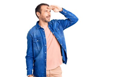 Gündelik kıyafetler giyen, mutlu ve gülümseyen genç, yakışıklı bir adam başıyla uzaklara bakıyor. arama kavramı. 